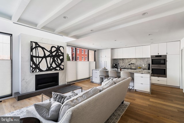 living room with beamed ceiling, a fireplace, and wood finished floors