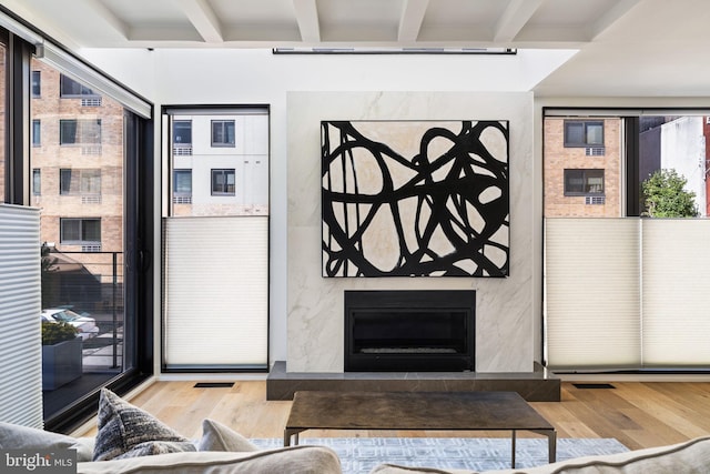 interior space featuring visible vents, beam ceiling, a high end fireplace, and light wood-style floors