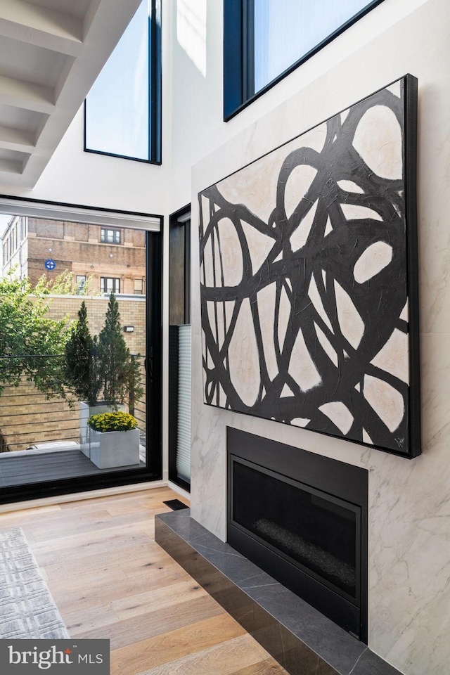 entryway with a towering ceiling, a premium fireplace, wood finished floors, and beamed ceiling