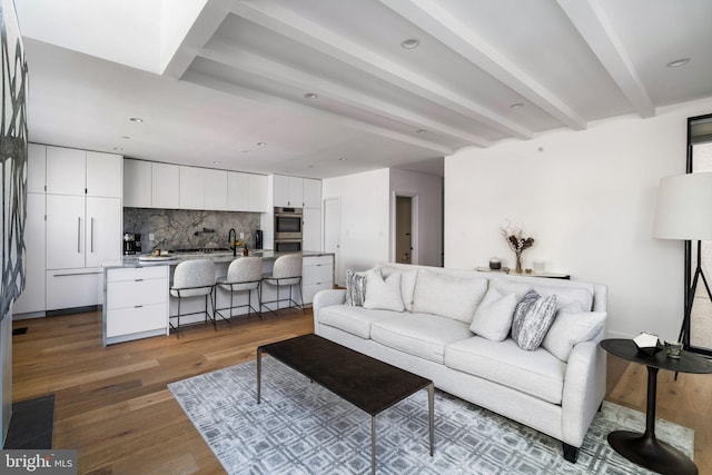 living area with recessed lighting, beam ceiling, and wood finished floors