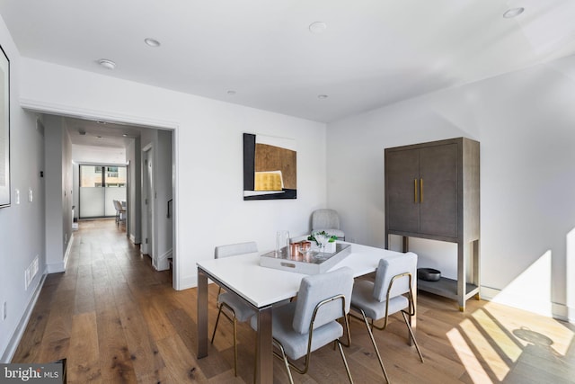 dining area with wood-type flooring, visible vents, and baseboards