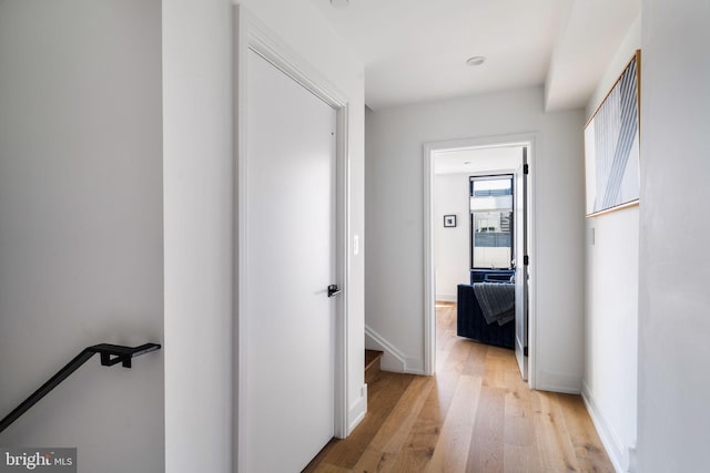 hall with light wood-type flooring and baseboards