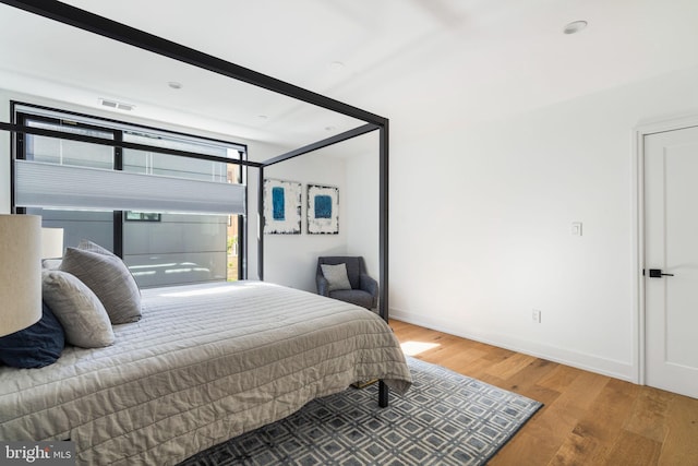 bedroom featuring baseboards, visible vents, and wood finished floors