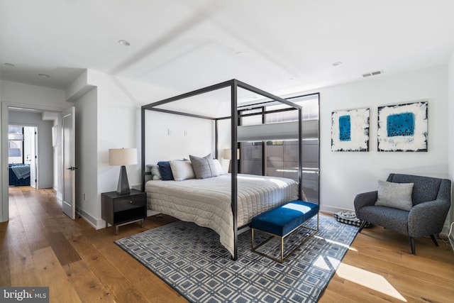 bedroom featuring hardwood / wood-style floors, visible vents, and baseboards