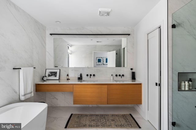 full bathroom featuring a freestanding tub, a sink, marble finish floor, a shower stall, and double vanity