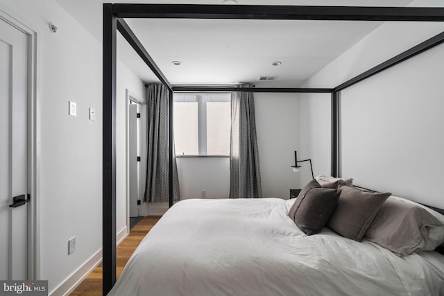 bedroom with wood finished floors, visible vents, and baseboards