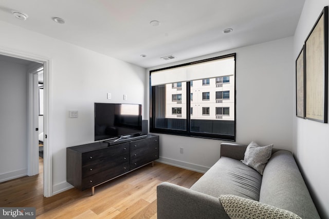 living room with visible vents, light wood-style flooring, and baseboards