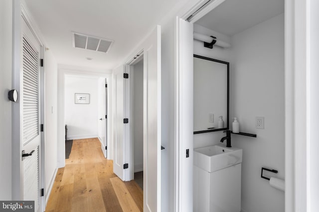 corridor with light wood-style floors and visible vents