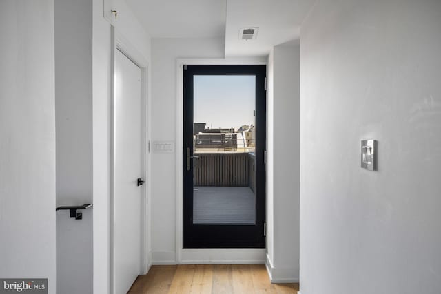 corridor with baseboards, visible vents, and light wood-style floors