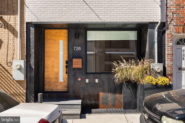 doorway to property featuring brick siding