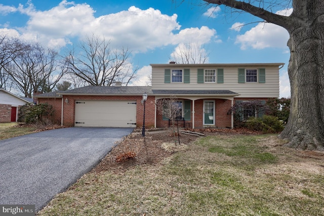 traditional-style house featuring aphalt driveway, a chimney, an attached garage, and brick siding