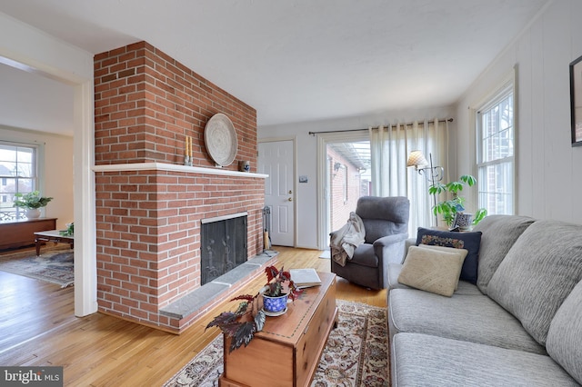 living room featuring a brick fireplace and wood finished floors