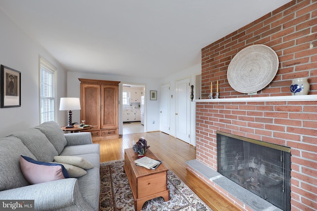 living room featuring a brick fireplace and light wood-style flooring