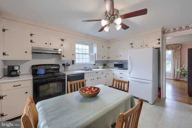 kitchen featuring under cabinet range hood, black range with electric stovetop, light countertops, freestanding refrigerator, and stainless steel microwave