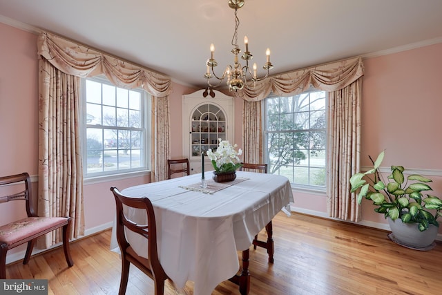 dining room with ornamental molding, light wood-type flooring, a wealth of natural light, and a chandelier