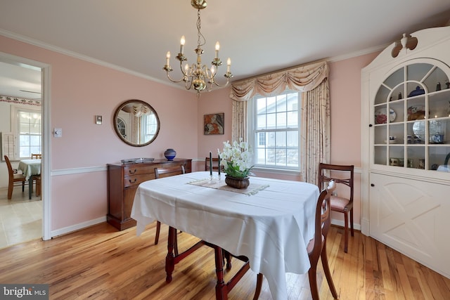 dining space with light wood-type flooring, an inviting chandelier, baseboards, and crown molding