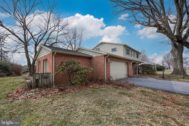 view of side of property featuring aphalt driveway, a lawn, and brick siding