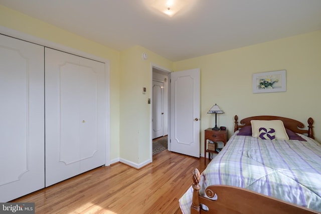 bedroom with light wood-style floors, baseboards, and a closet