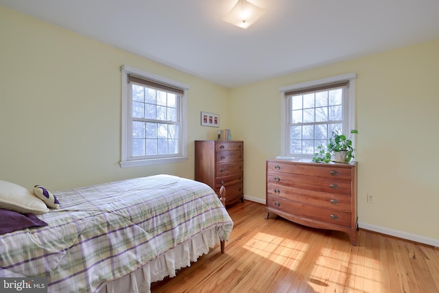 bedroom featuring baseboards, multiple windows, and hardwood / wood-style floors