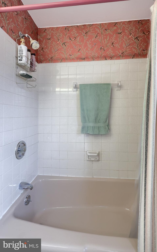 bathroom featuring wallpapered walls and shower / bathtub combination with curtain