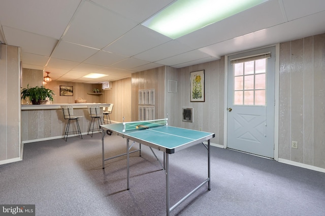 playroom with carpet, wooden walls, indoor bar, and a drop ceiling