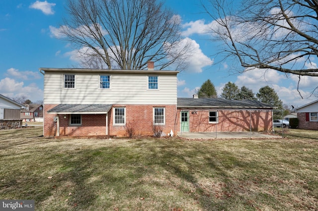 back of property featuring a yard, a patio area, a chimney, and brick siding