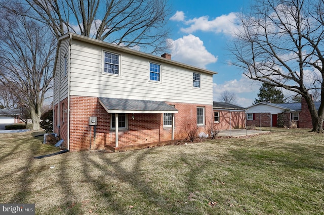 rear view of house with a chimney, a lawn, a patio, and brick siding