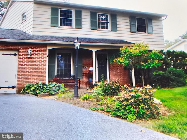 traditional-style house with an attached garage, a porch, and brick siding