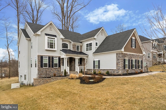 view of front facade with stone siding, a shingled roof, and a front yard