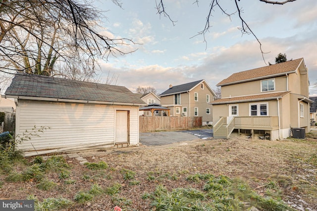 back of property with an outbuilding, central AC, fence, and stucco siding