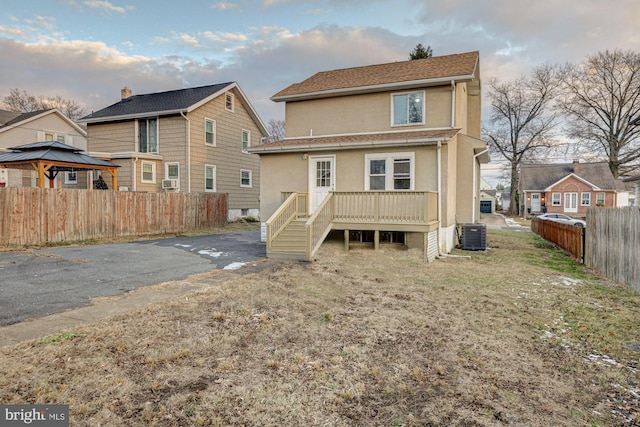 rear view of house with cooling unit, stucco siding, fence, a deck, and a residential view