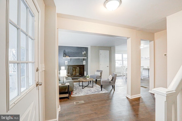 foyer featuring baseboards, a fireplace, visible vents, and dark wood finished floors