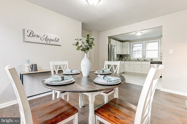 dining space featuring light wood-type flooring and baseboards