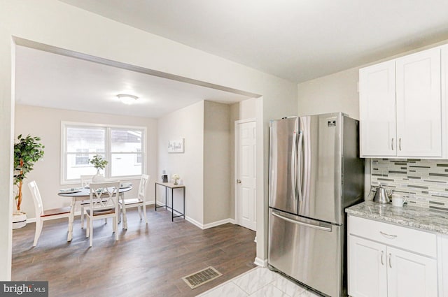 kitchen with freestanding refrigerator, visible vents, backsplash, and white cabinetry