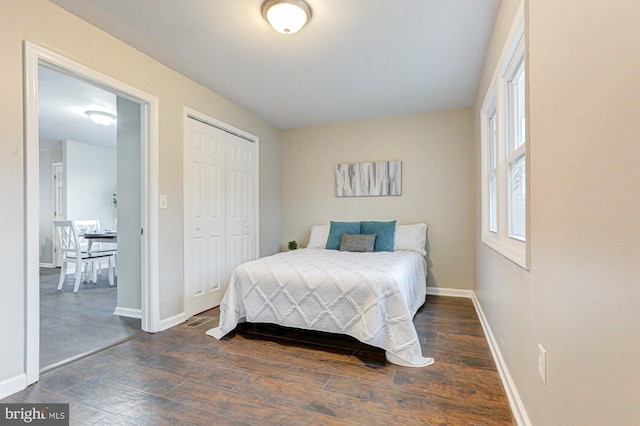 bedroom with a closet, baseboards, and dark wood-type flooring