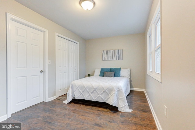 bedroom with a closet, dark wood finished floors, and baseboards