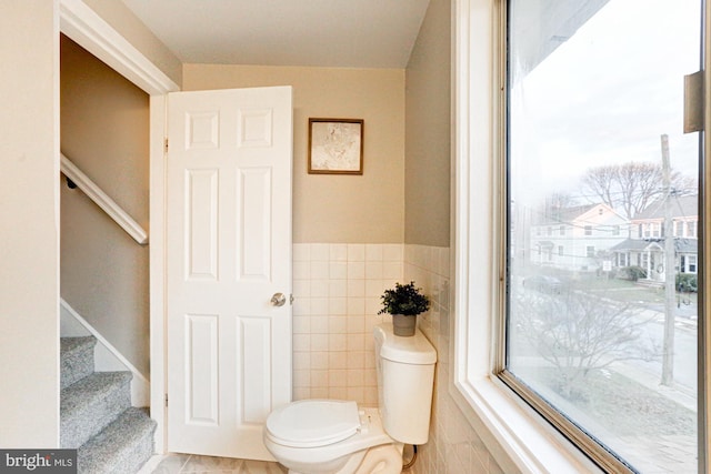 bathroom featuring toilet and tile walls