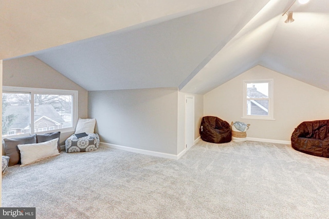 living area featuring carpet floors, baseboards, and vaulted ceiling