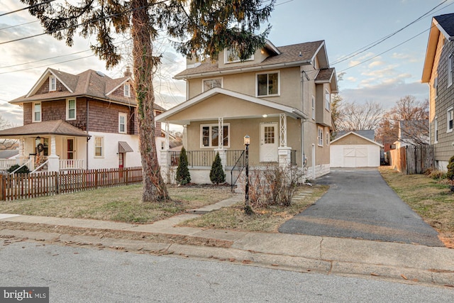 traditional style home with aphalt driveway, an outbuilding, a detached garage, covered porch, and fence