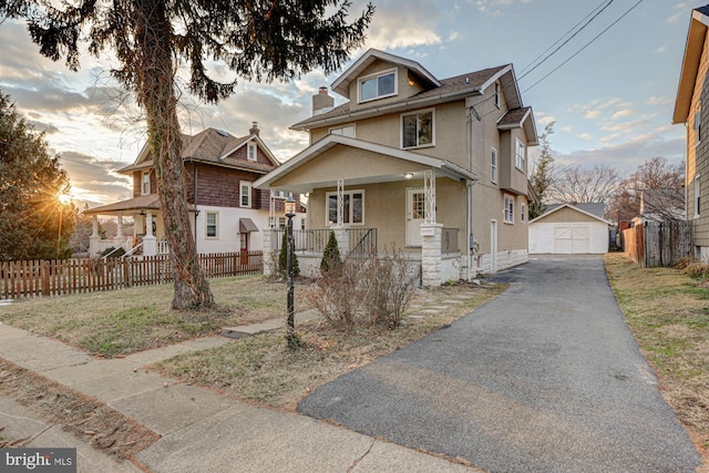 traditional style home with covered porch, a detached garage, fence, an outdoor structure, and stucco siding