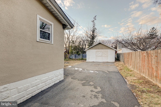 view of side of property featuring an outbuilding, a storage unit, fence, and stucco siding