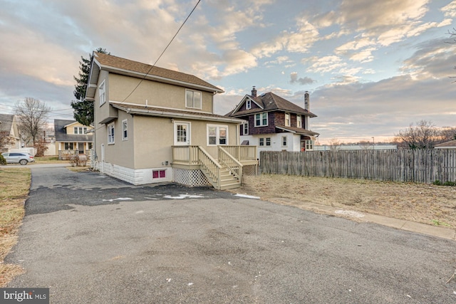 rear view of house featuring fence and stucco siding