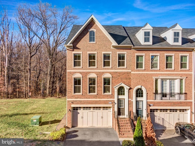 view of property featuring a garage, brick siding, a front yard, and aphalt driveway