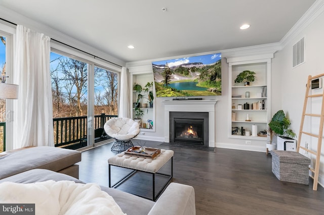 living room featuring dark wood-type flooring, a fireplace with flush hearth, visible vents, built in features, and crown molding