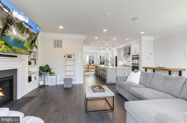 living area featuring recessed lighting, visible vents, ornamental molding, dark wood-style floors, and a glass covered fireplace