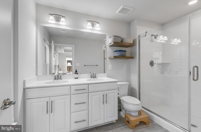 full bathroom featuring double vanity, visible vents, toilet, a stall shower, and a sink