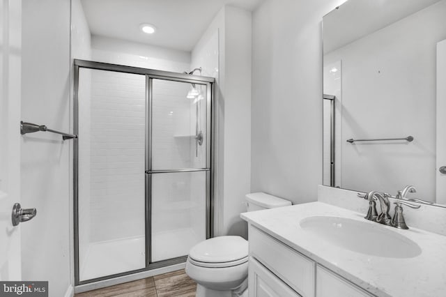 full bath featuring vanity, wood finished floors, a shower stall, and toilet