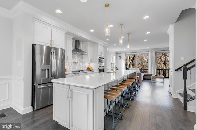 kitchen with wall chimney exhaust hood, appliances with stainless steel finishes, light countertops, white cabinetry, and a sink