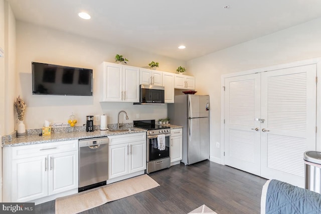 kitchen featuring dark wood-style floors, appliances with stainless steel finishes, white cabinetry, a sink, and recessed lighting