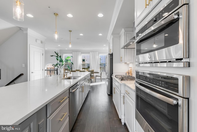 kitchen featuring ornamental molding, light countertops, appliances with stainless steel finishes, and a sink